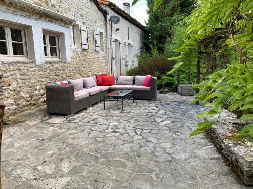 a couch sitting on a stone patio in front of a building at Uniquely Private Holiday Villa in the Charente in Puyréaux