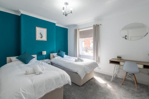 two beds in a room with blue walls and a desk at Kingsway Property in Goole