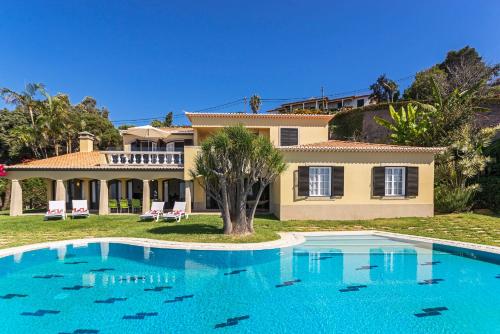 a large house with a swimming pool in front of it at Vila Eucalipto by An Island Apart in Funchal