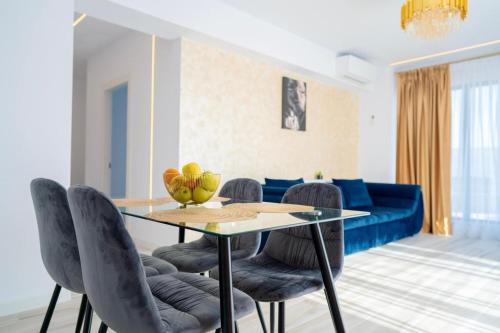 una sala da pranzo con tavolo, sedie e divano blu di Bel Air Mamaia Nord Complex - Apartament Delux a Mamaia