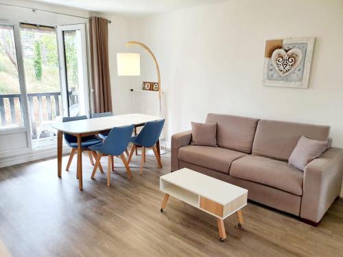 a living room with a couch and a table and chairs at Le bord de plage in Bénerville-sur-Mer
