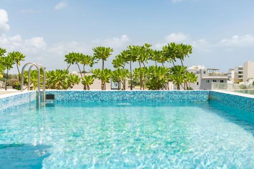 een zwembad met palmbomen op de achtergrond bij Boho Lofts & Studios in Playa del Carmen
