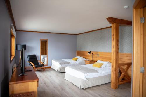 Una habitación de hotel con dos camas y un televisor. en Hotel Puelche, en Puerto Varas