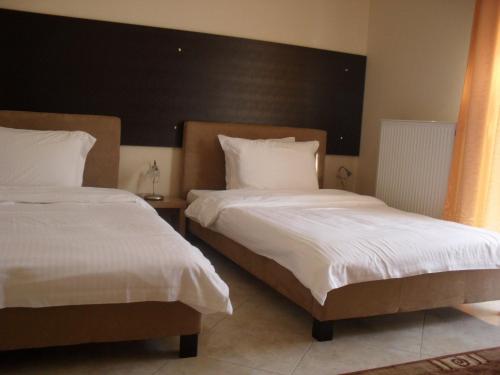 a bedroom with two beds with white blankets and pillows at Kyknos De Luxe Suites & Rooms in Kastoria