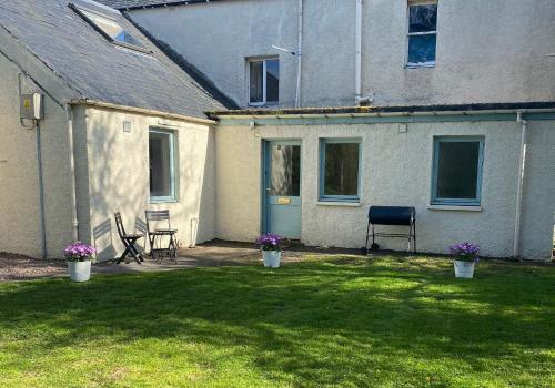 a yard with chairs and a house with a blue door at Jack’s Roost in Clovenfords