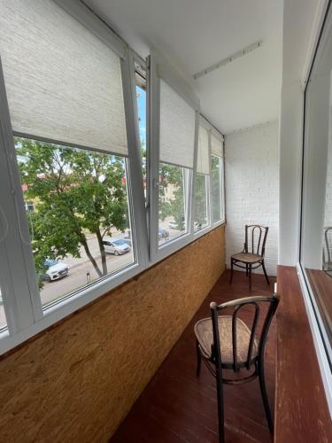 a room with windows and a chair and a table at APARTMENTS IN THE CITY CENTER BIRŽAI Vytauto g22 in Biržai