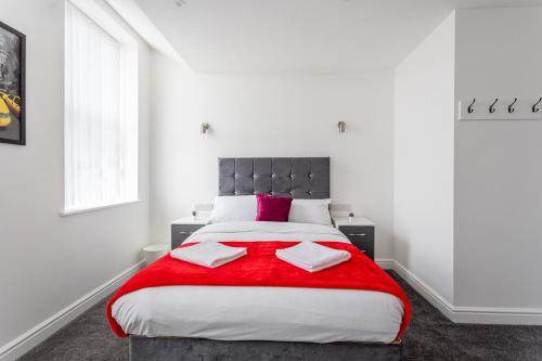a bedroom with a large bed with a red blanket at Dusties Hotel in Rotherham