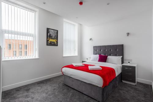 a bedroom with a large bed with a red blanket at Dusties Hotel in Rotherham
