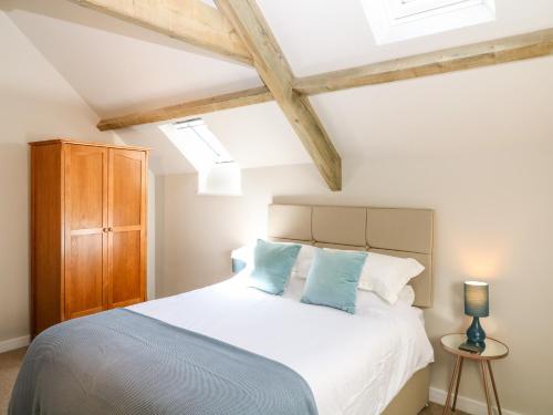 1 dormitorio con cama blanca y almohadas azules en Cherrywood Barn, en South Petherton