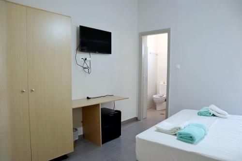 1 dormitorio con 1 cama y escritorio con TV en Το Κοράλι, en Amarinto