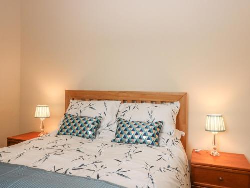 Schlafzimmer mit einem Bett mit blauen und weißen Kissen in der Unterkunft Gardener's Cottage in Forfar