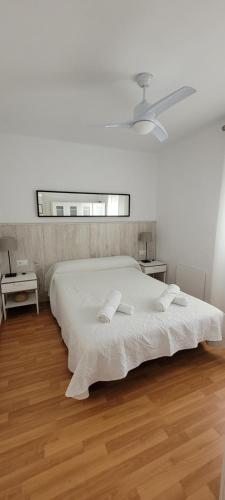 a white bedroom with a large bed and a window at Apartamento Catalina, en el casco histórico. in Ronda