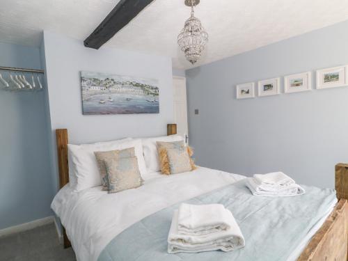 a bedroom with a bed with white sheets and a chandelier at Old Town House in Dawlish