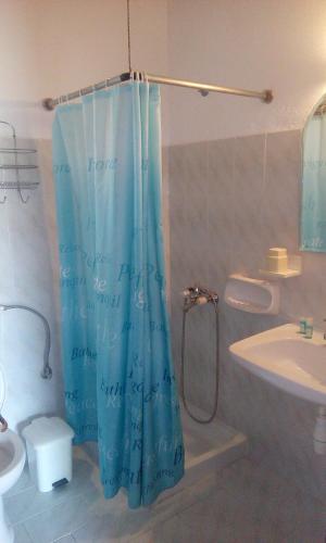a bathroom with a blue shower curtain and a sink at Villa Yannis 1 in Roda