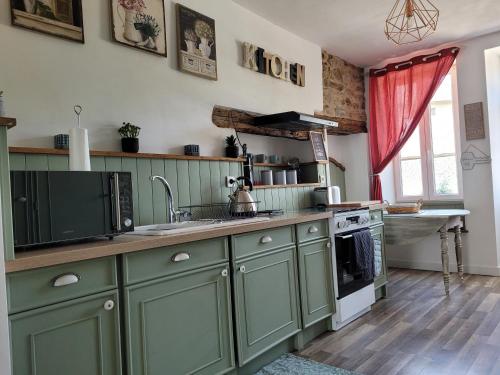 - une cuisine avec des placards verts et un évier dans l'établissement Gîte du Vieux Lavoir, à Arnac-Pompadour