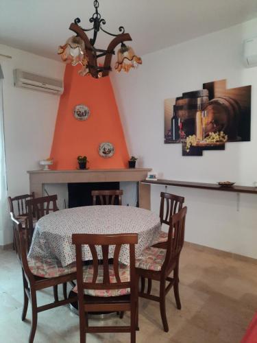 una sala da pranzo con tavolo, sedie e parete arancione di ALBA MOZZAFIATO a Lanusei
