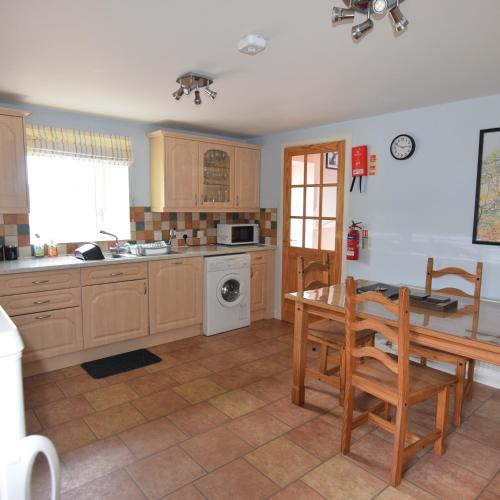 una cocina con armarios de madera, mesa y fregadero en Moray Cottages, en Dufftown