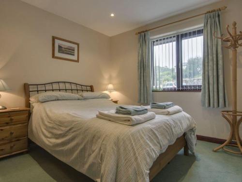 - une chambre avec un lit et des serviettes dans l'établissement Columbine Cottage, à Bude
