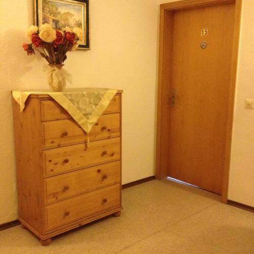 a dresser with a vase of flowers on top of it at Hotel Elsenztal in Bammental
