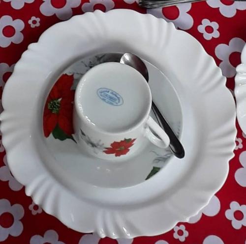 a white plate with a cup and spoon on a table at Aconchego Caminho das Cachoeiras in Rio Acima
