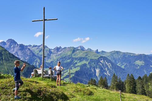 a group of people standing on a hill with a cross at Neuhornbachhaus in Schoppernau