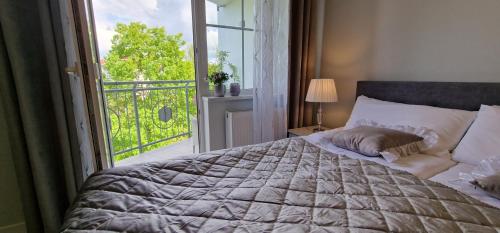 a bedroom with a large bed with a window at Apartamenty Hexagon nr 23 in Grzybowo