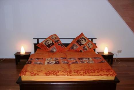 a bed with an orange comforter and two lamps at Apartments Mester in Xanten