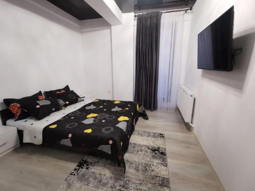 a bedroom with a bed with a black comforter at Lumandi LS residence in Mamaia Nord