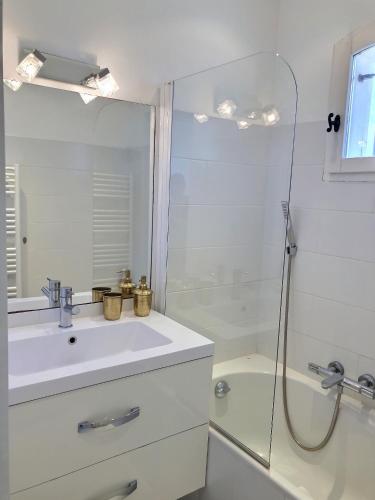 une salle de bain blanche avec un lavabo et une douche dans l'établissement L’atypique : 2 chambres // Piscine // parking, à Saint-Tropez