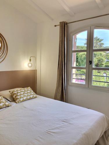 une chambre avec un lit blanc et une fenêtre dans l'établissement L’atypique : 2 chambres // Piscine // parking, à Saint-Tropez
