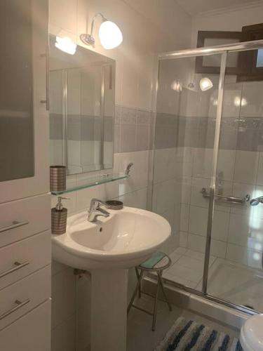 a white bathroom with a sink and a shower at Κυκλαδίτικη μεζονέτα με πισίνα και απεριόριστη θέα in Sinétion