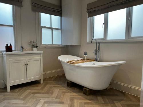 a white bath tub in a bathroom with windows at Entire apartment, 10mins from Cotswolds, Child friendly, Great Location & plenty of free parking nearby in Evesham