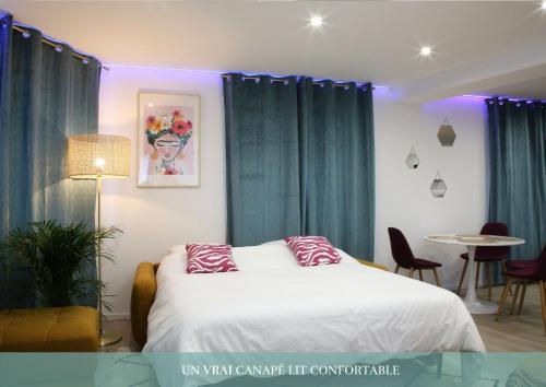 a bedroom with a bed with blue curtains and a table at La Loge en Or - Parking public - Triplex - Proche centre et autoroute in Lens