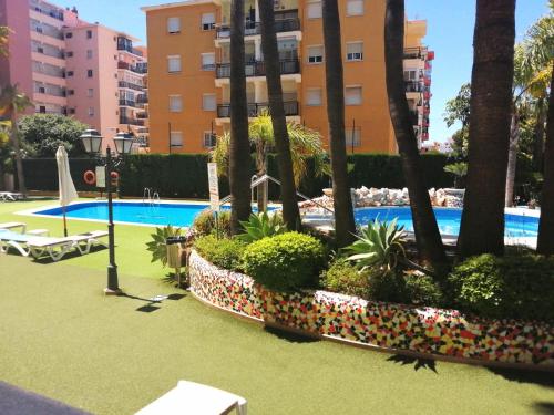 un complejo con piscina y palmeras en Fuengirola Apartamento vacacional MEDITERRANEO REAL, en Fuengirola