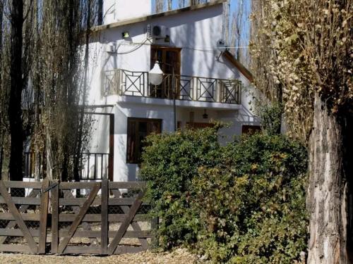 a white building with a balcony and a fence at Los Abedules Bungalow in Malargüe