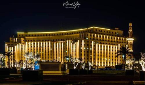 a large yellow building with a clock tower at night at One Season Hotel in Cairo