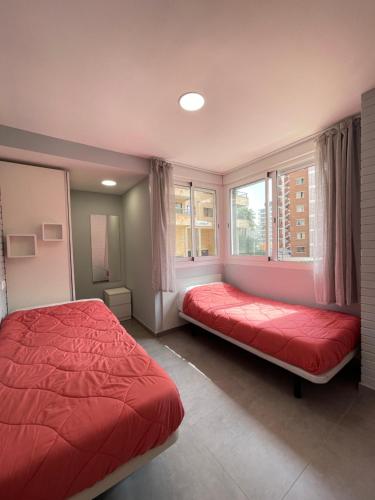 sypialnia z czerwonym łóżkiem i 2 oknami w obiekcie New Square Ocean w mieście Benidorm