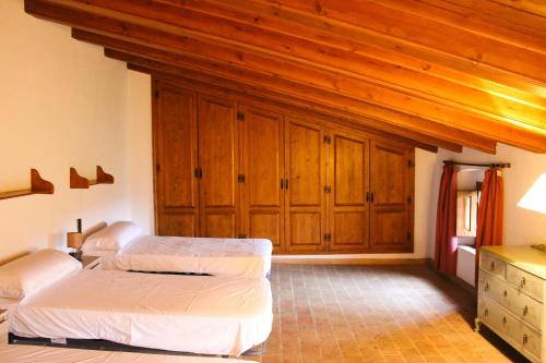 um quarto com 2 camas e armários de madeira em Mas Goy, casa rural con piscina em Girona