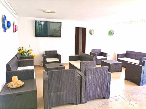 a waiting room with chairs and a tv on the wall at Hotel Arabesco in Rimini