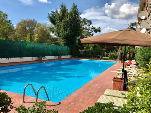a swimming pool with chairs and an umbrella at La Casa Di Camp - Apartment in Rome