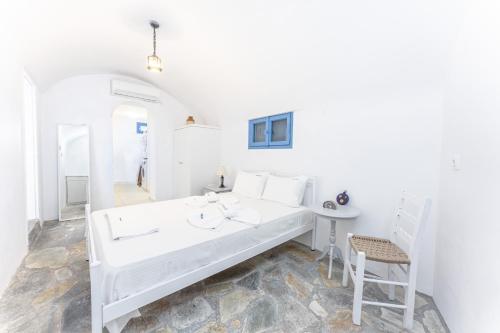 a white room with a bed and a chair at Captain's Quarters in Vóthon