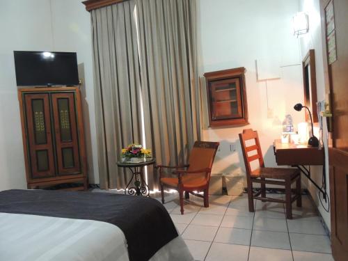 a hotel room with a bed and a table and chairs at Hotel Concierge Plaza Colima in Colima