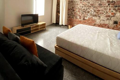 1 dormitorio con cama, sofá y TV en 107 SUITES DONCELES CENTRO HISTÓRICO CDMX, en Ciudad de México