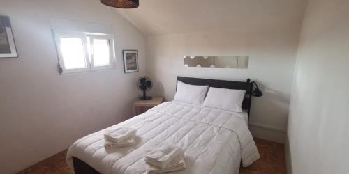 um quarto com uma cama com lençóis brancos e uma janela em Duque de conventus em Lisboa