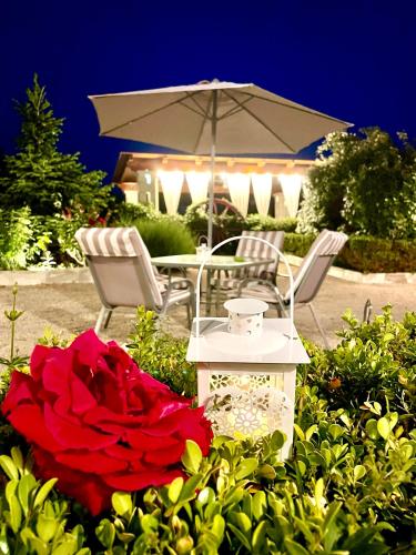 a table and chairs with an umbrella and a red rose at Mirella Charming in Alberobello