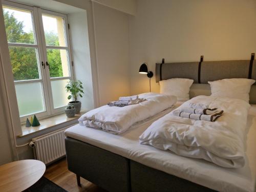 1 dormitorio con 2 camas con sábanas blancas y ventana en Guesthouse, en Sønderborg