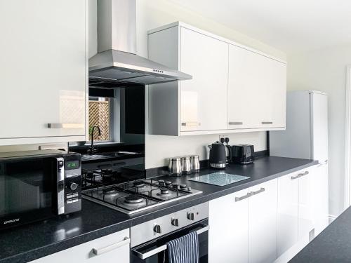 a white kitchen with a stove and a microwave at Cedar House - Quaint Victorian Home With Free Parking in York