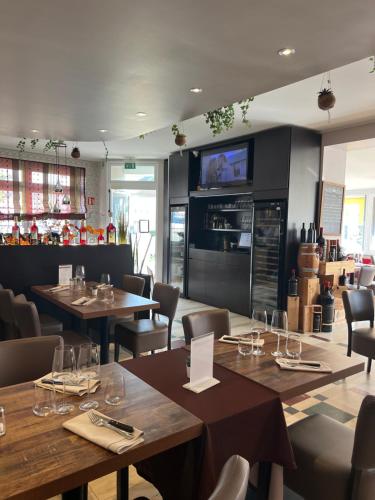 a restaurant with wooden tables and chairs and a tv at Auberge La Veranda in Luxembourg