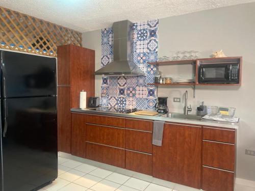 uma cozinha com armários de madeira e um frigorífico preto em Boquerón Beach Apartment.- Guarionex 207 em Cabo Rojo
