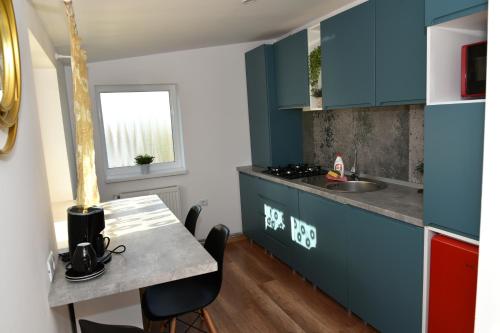 a kitchen with blue cabinets and a table with chairs at ApartHotel Dominic Residence in Alba Iulia